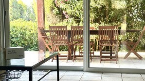 Un patio con sedie e tavolo in legno, una porta vetrata che dà sull'esterno e un cartello con la scritta 'You are welcome'.
