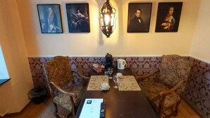 Un comedor con una mesa dispuesta para dos personas, sillas, una lámpara y cuadros en la pared.