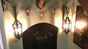Un pasillo con chimenea, cabezas de animales montadas en la pared y faroles fijados a la pared.