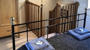 A bedroom with a wooden wardrobe, a bed with a black metal headboard, and a heart-shaped light fixture on the wall. - Award Winning Little Gem on the Historic Cartway (Bridgnorth)