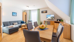 Una sala de estar moderna con sofá, mesa de comedor, sillas y área de cocina.