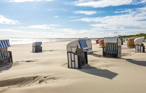 Strandkörbe mit Sonnenschirmen an einem Sandstrand.