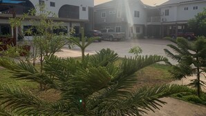 A courtyard with a building, parked cars, and cacti. - Dafika Lodge (Tema)