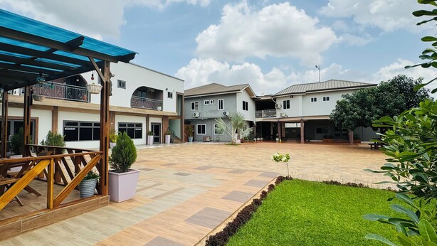 A spacious courtyard with a covered seating area, a restaurant, and multiple residential buildings. - Dafika Lodge (Tema)