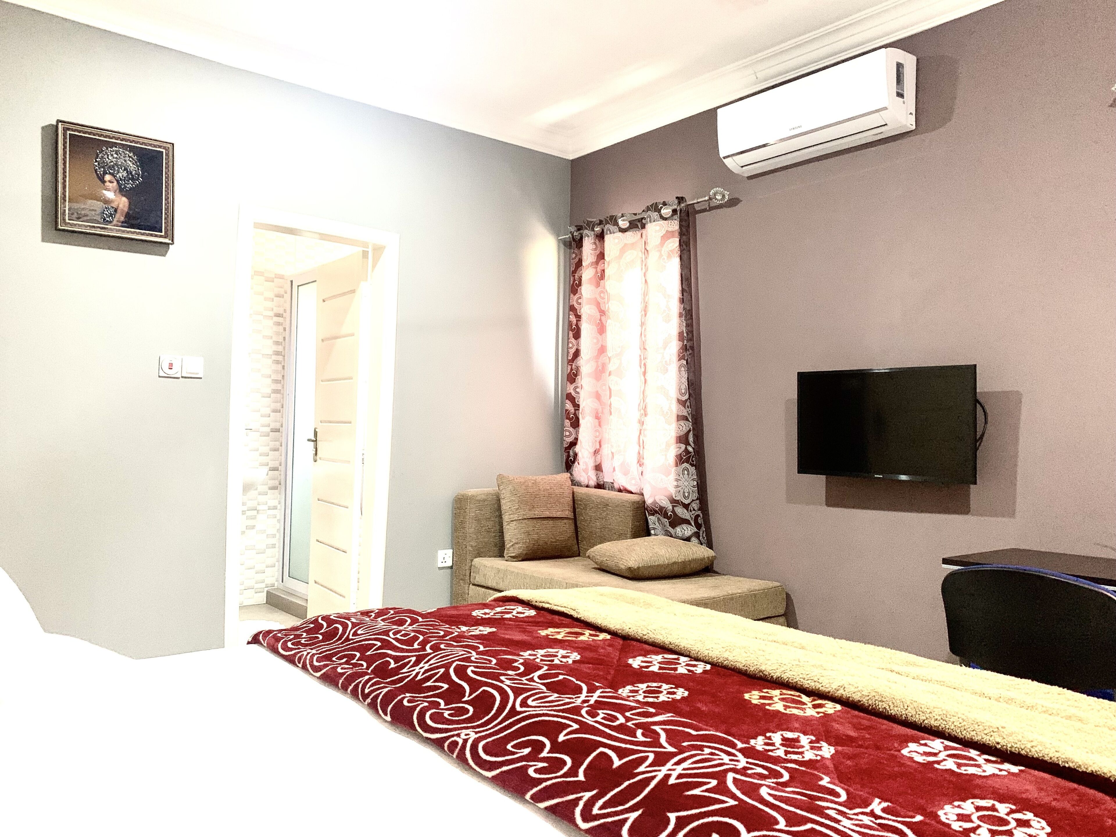 A hotel room with a bed, a TV, a sofa, and a patterned rug.