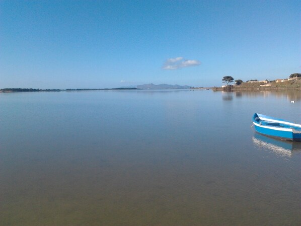 A calm lake with a small blue boat anchored near the shore. - Bibbo - Holiday home in the Marsala Islands Reserve (Marsala)