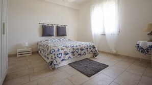 Une chambre à coucher avec un lit, une table de chevet, une lampe, une fenêtre avec des rideaux et un tapis.