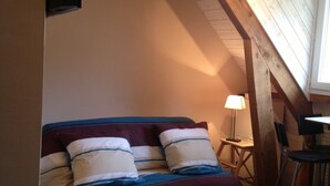 Ein Schlafzimmer mit Bett, Nachttisch, Sessel und Lampe.