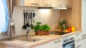 A modern kitchen with wooden cabinets, a stainless steel sink, and a built-in oven. - Bungalow Möwe (opposite the “Hus Günter”) (Seebad Ahlbeck, Mecklenburg-Vorpommern)