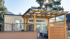 A covered patio area with a pergola, a wooden fence, and a table with chairs. - Bungalow Möwe (opposite the “Hus Günter”) (Seebad Ahlbeck, Mecklenburg-Vorpommern)