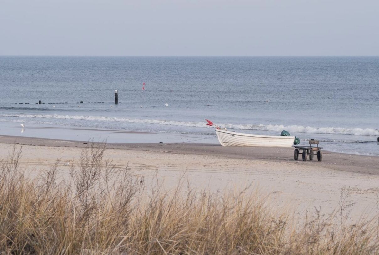 A beach with a boat tied to a post, a small table, and a cart.