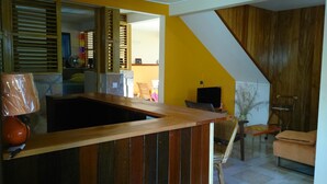 Une pièce avec un bureau en bois, une chaise, un téléviseur et une plante.