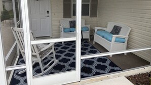 A screened porch with two white wicker chairs, a rocking chair, and a patterned rug. - Village of Fernandina - free use of golf cart with liability waiver (The Villages)