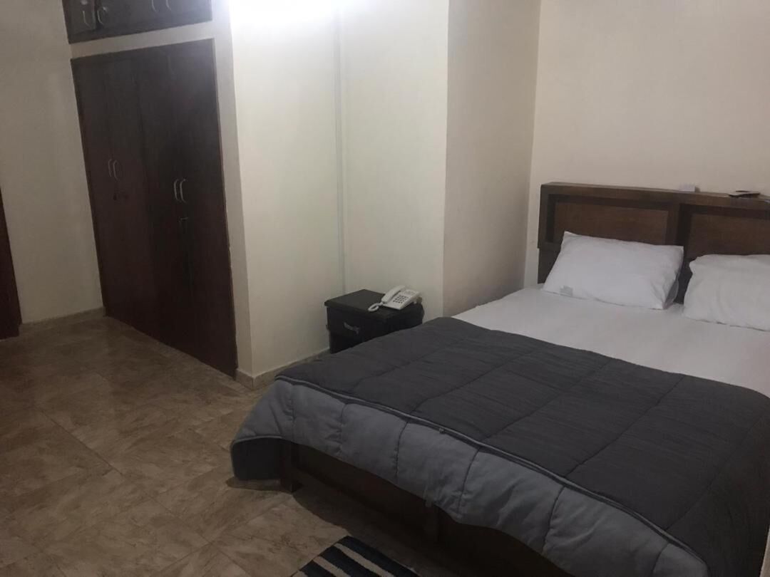 Une chambre à coucher comprenant un lit, une table de chevet, une armoire et un téléphone.