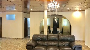 Un'ampia hall con un divano in pelle, un lampadario e una sala conferenze visibile attraverso un arco.