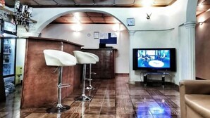 Angolo bar con televisore, sgabelli da bar e un lampadario.