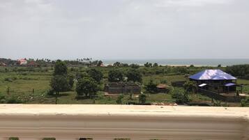 A balcony with a view of a coastal landscape, including houses and greenery.