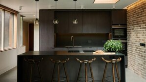 A modern kitchen with a central island, bar stools, pendant lighting, and a skylight. - Weymouth Mews (London)