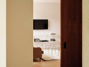 A modern living room with a flat-screen TV mounted on the wall, a sofa, and a coffee table.