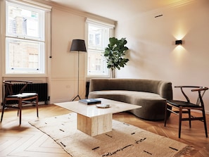 A modern living room with a sofa, two chairs, a coffee table, and a floor lamp.