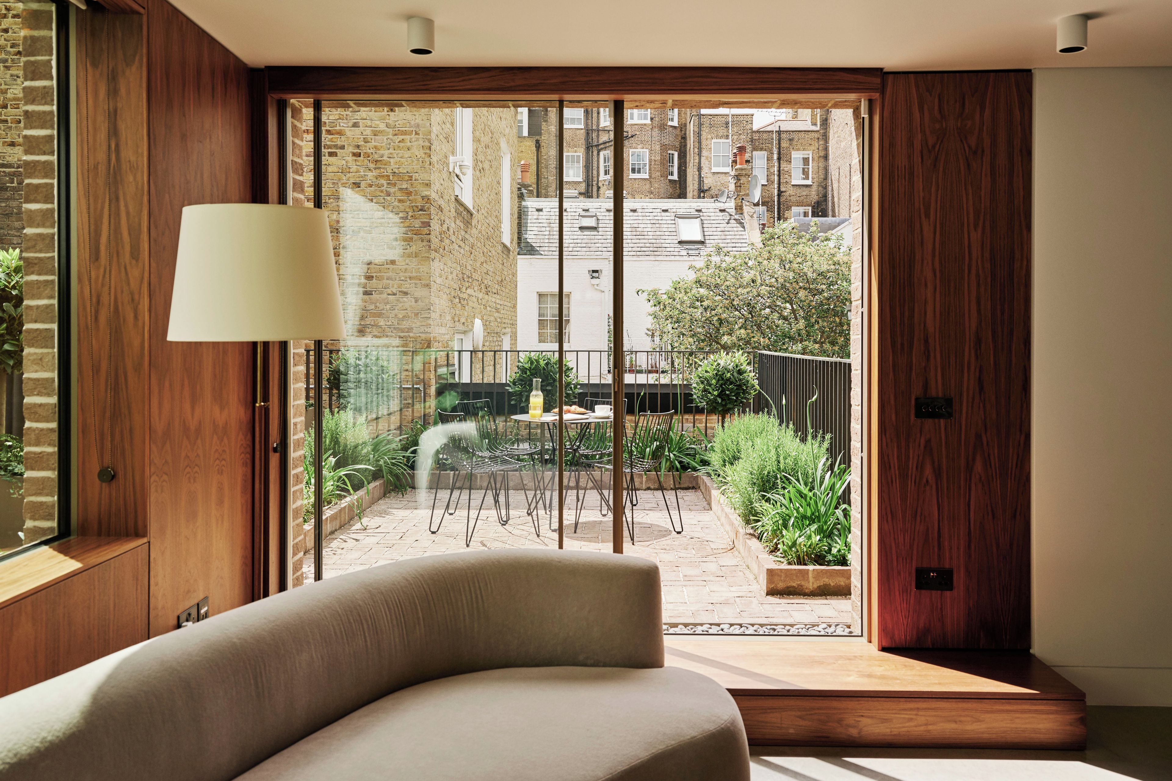 A modern interior with a sofa, a large window, and a view of a brick building outside.