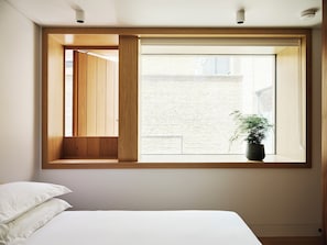 A bedroom with a large window, a bed, and a potted plant. - Weymouth Mews (London)