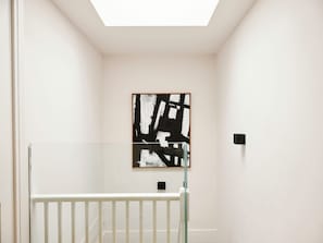A minimalist room with a white wall, a black and white abstract painting, and a white railing. - Weymouth Mews (London)