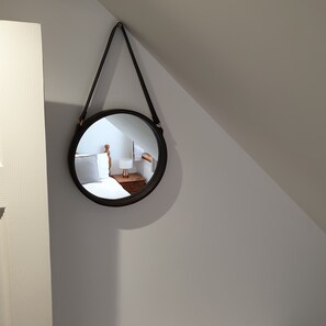 A round mirror with a black frame hanging on a plain wall. - Aldos Place (Dingwall)