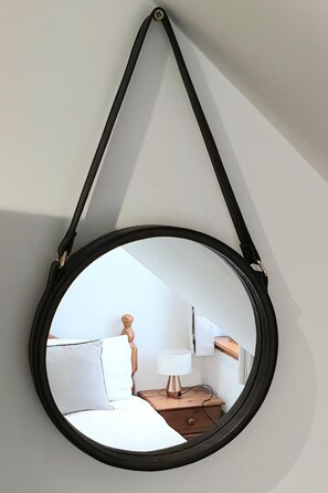 A round mirror with a black frame hanging on a wall. - Aldos Place (Dingwall)