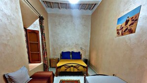 A small, cozy room with a bed, a sofa, and a rug. - Chambres d'Hôtes Riad Dar Tazoulte (Agdz)