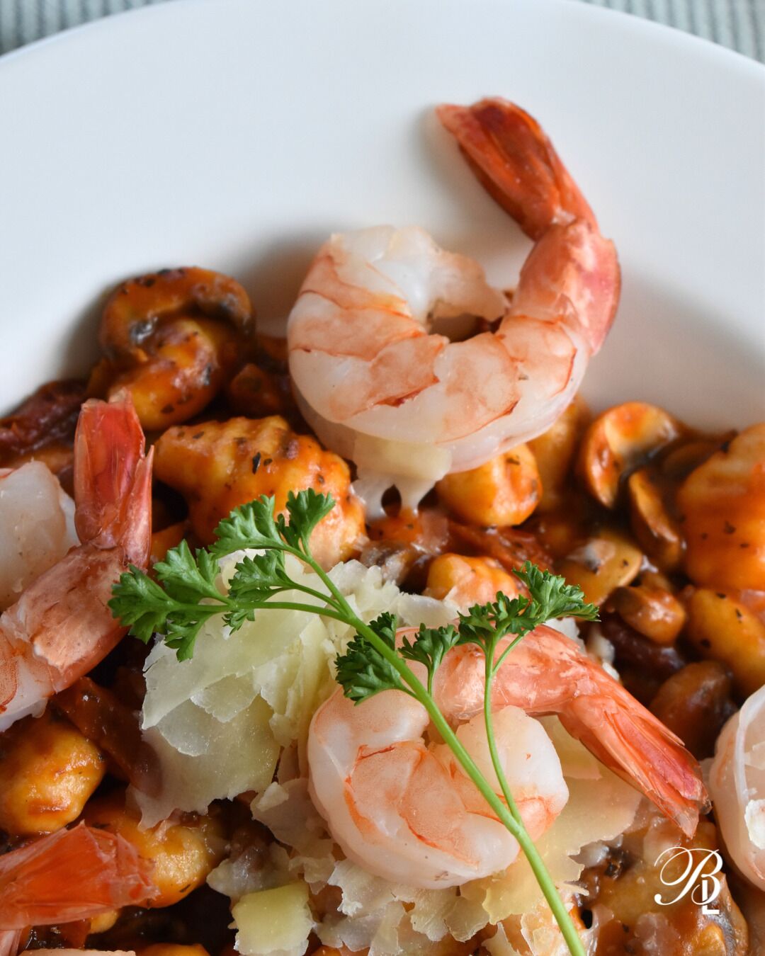 Plato de mariscos con camarones, mejillones y papas, adornado con perejil.