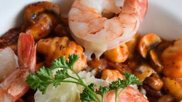 Plato de mariscos con camarones, mejillones y papas, adornado con perejil.