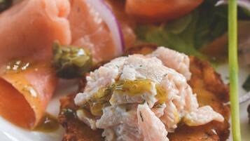 A plate with a variety of foods including a piece of fish, a slice of tomato, and some greens.