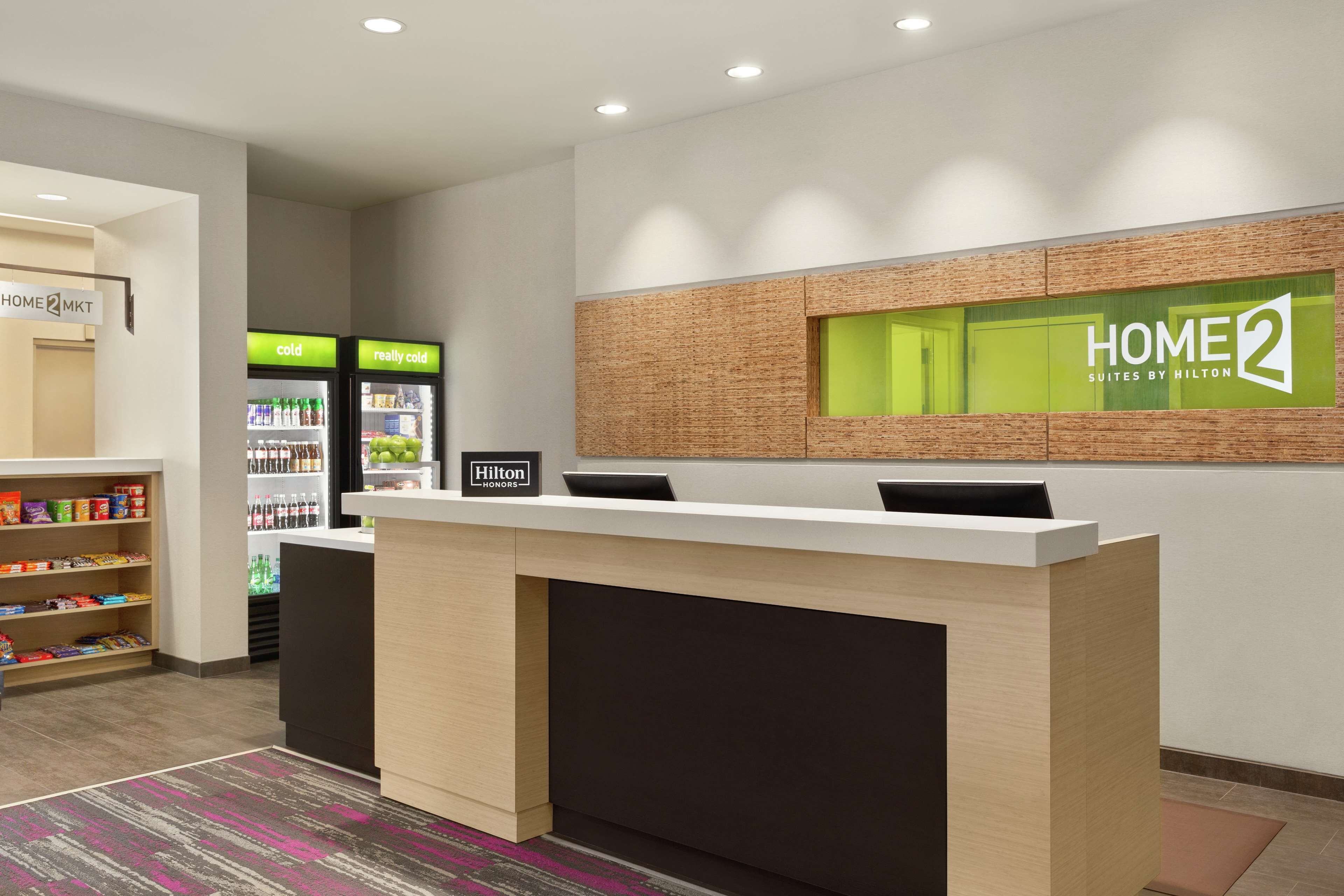 Un espace d’accueil comprenant un comptoir de réception, un mini-bar et un réfrigérateur avec les mentions « froid » et « très froid ».
