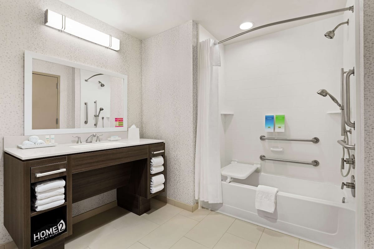 Une salle de bain moderne avec un meuble-lavabo à deux vasques, une douche avec une porte en verre et une baignoire.