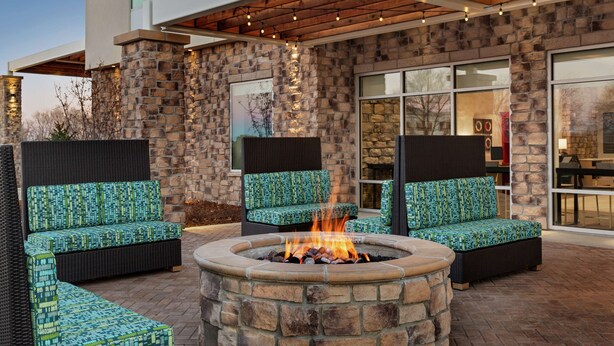 A stone fire pit surrounded by outdoor seating with patterned cushions.