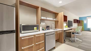 A modern kitchen with a microwave, coffee maker, and a sink. There is a wooden cabinet with drawers and a dishwasher.