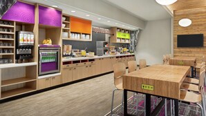 A modern kitchen with wooden cabinets, a refrigerator, and a built-in coffee machine.
