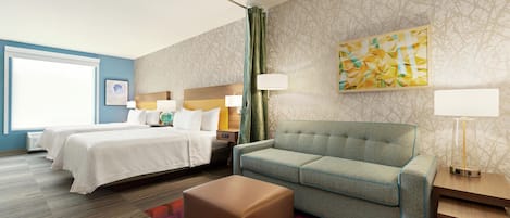 A hotel room with a bed, a sofa, a small table, and a lamp.