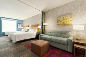 Une chambre d’hôtel avec un lit, un canapé, une petite table et une lampe.
