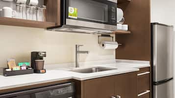 A modern kitchen with a built-in microwave, stainless steel sink, and a coffee maker.