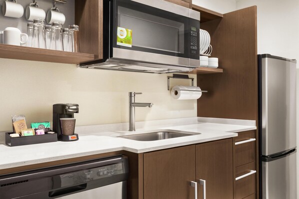 A modern kitchen with a built-in microwave, stainless steel sink, and a coffee maker.