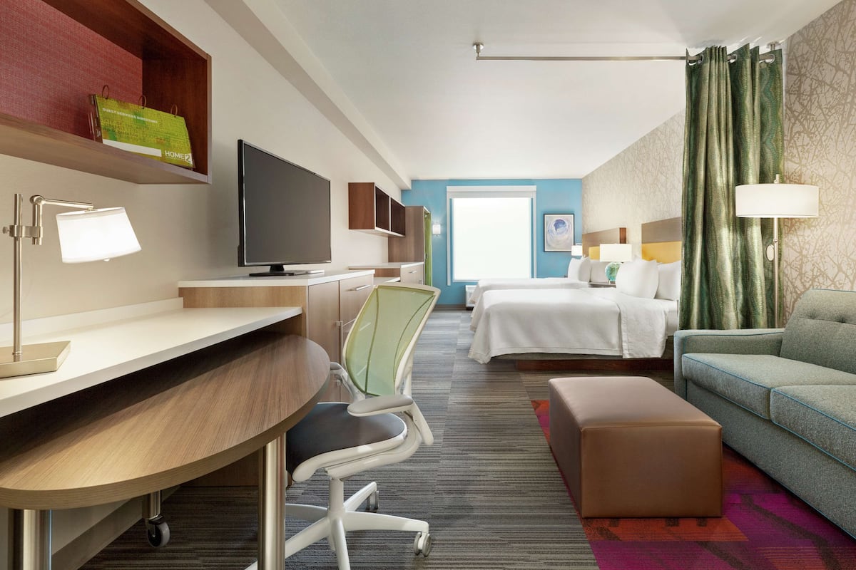 Une chambre d’hôtel équipée d’un bureau, d’une chaise, d’une télévision, d’un lit et d’un canapé.