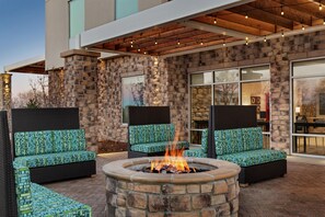 A stone fire pit surrounded by outdoor seating with patterned cushions.