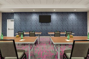 A conference room with four tables, chairs, a flat-screen TV, and a refrigerator.