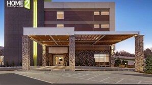 A modern hotel entrance with a covered lobby, stone pillars, and a clear sky.