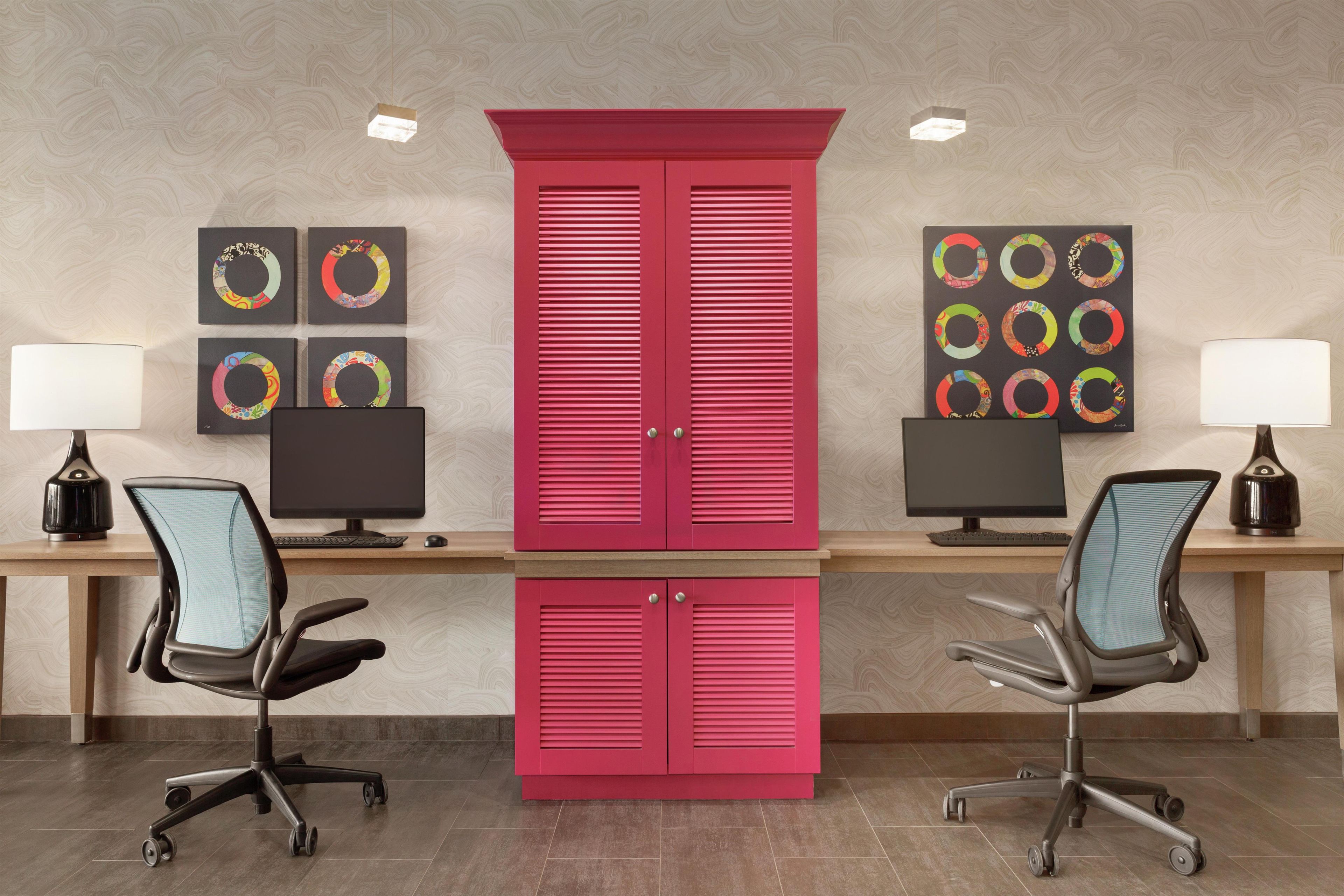 Un espace de bureau moderne comprenant deux bureaux, chacun équipé d’un ordinateur, d’une lampe et d’un fauteuil ergonomique.