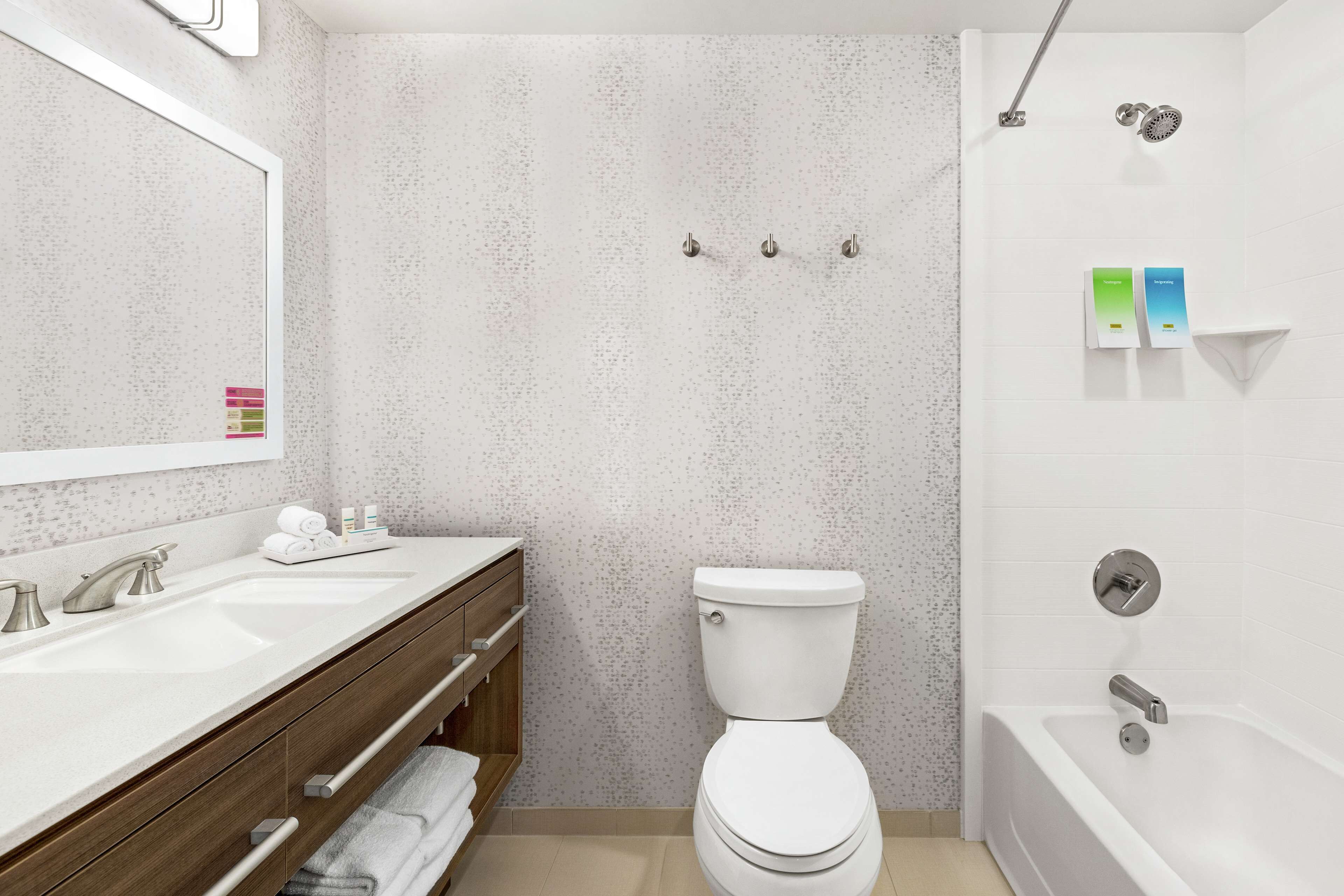 A modern bathroom with a double sink vanity, a toilet, and a bathtub.
