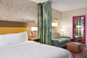 Une chambre d’hôtel avec un lit, une table de chevet, une lampe, un canapé, un miroir et une moquette.