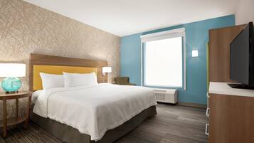 Une chambre d’hôtel avec un lit, une télévision, une fenêtre et un mur décoré d’un motif représentant un arbre.